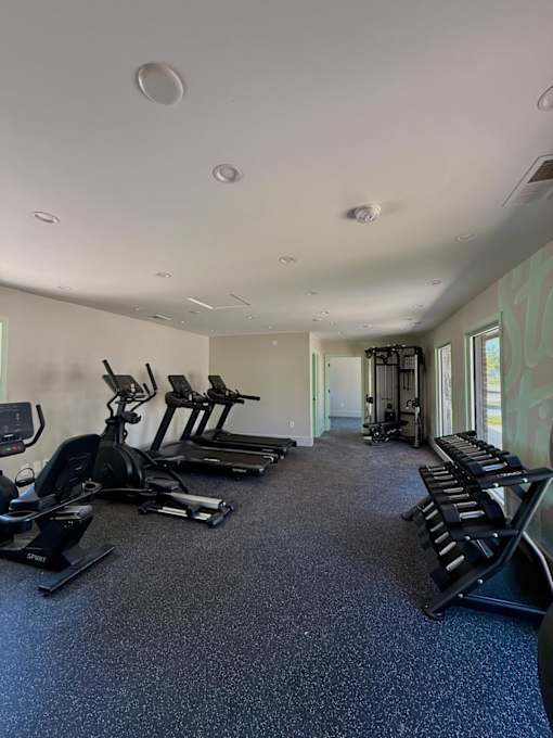 A spacious gym with treadmills, elliptical machines, and stationary bikes.