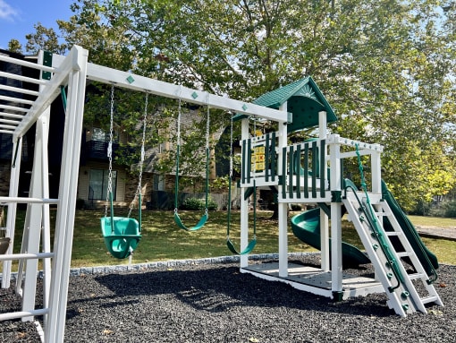 a playground with a swing set and a play house