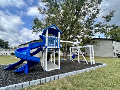 a playground with a blue slide and swing set