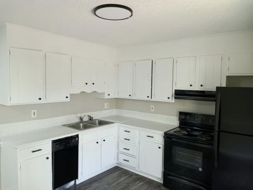 an empty kitchen with white cabinets and black appliances