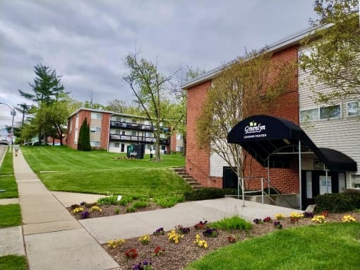 a sidewalk in front of a brick building with a black umbrella