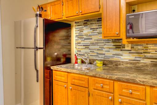 A kitchen with a refrigerator, cabinets, and a microwave.