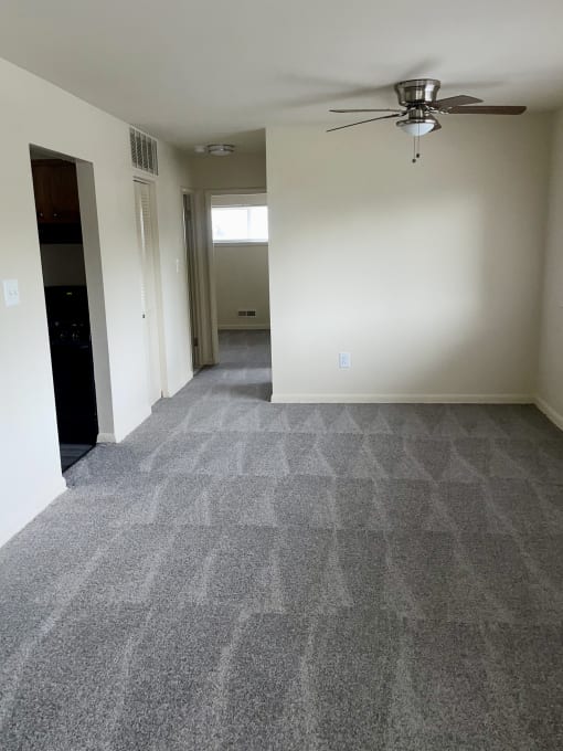 an empty living room with carpet and a ceiling fan