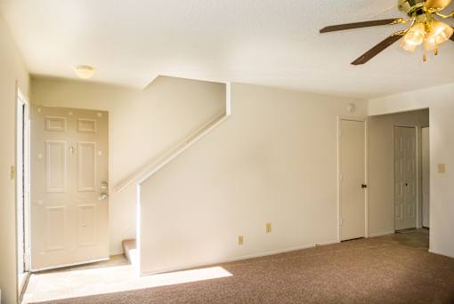 A room with a staircase and a ceiling fan.