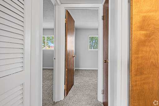 A hallway with a white door and a brown door.