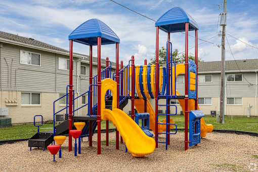 A playground with a yellow slide and blue and red towers.