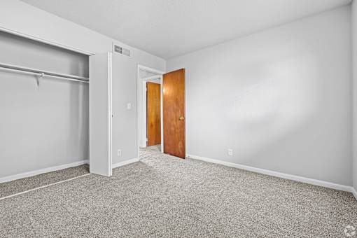 A room with a grey carpet and a white wall.