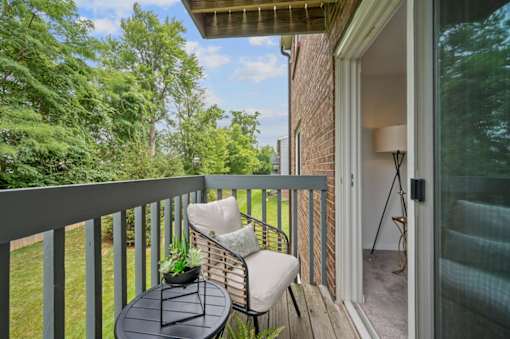A balcony with a table and chairs overlooking a green lawn.