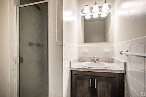 A bathroom with a sink, mirror, and shower.