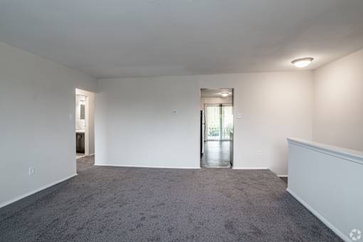 A large empty room with a carpeted floor and white walls.