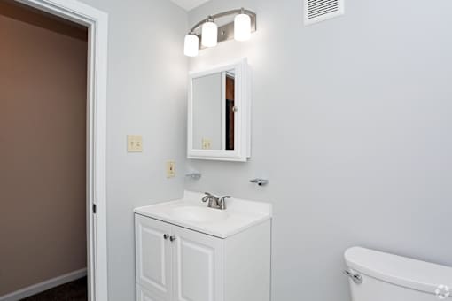 A white bathroom vanity with a mirror and lights above it.