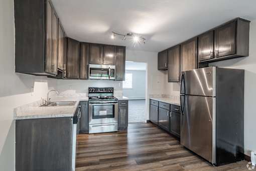 A modern kitchen with dark wood cabinets and stainless steel appliances.