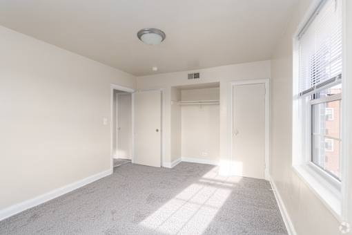 A spacious room with a carpeted floor and a window on the right side.