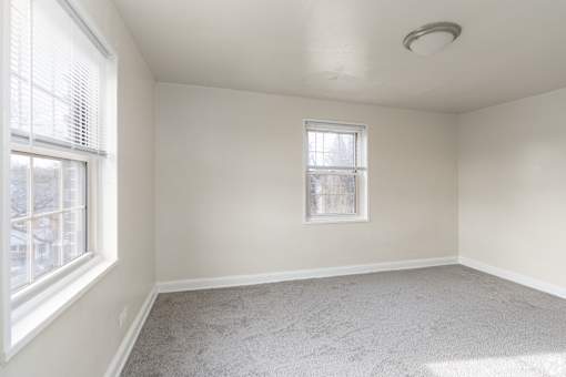 A room with a window and a carpeted floor.