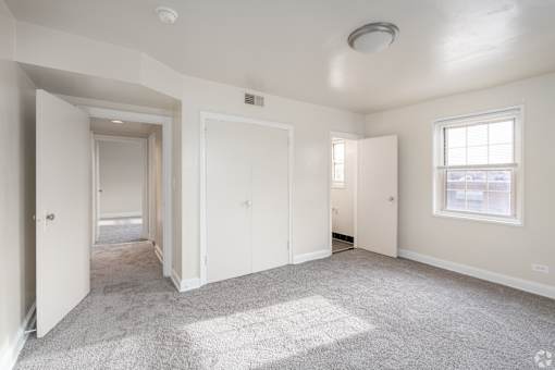 A spacious, empty room with white walls and carpeted floor.