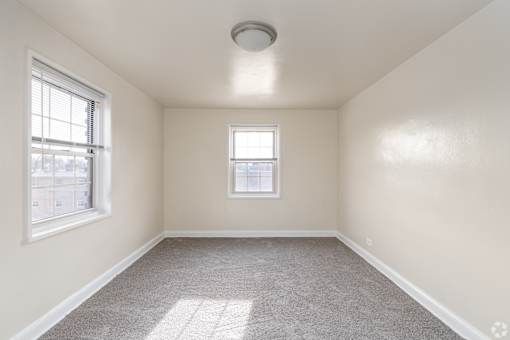 A room with a carpeted floor, a window, and a ceiling light fixture.