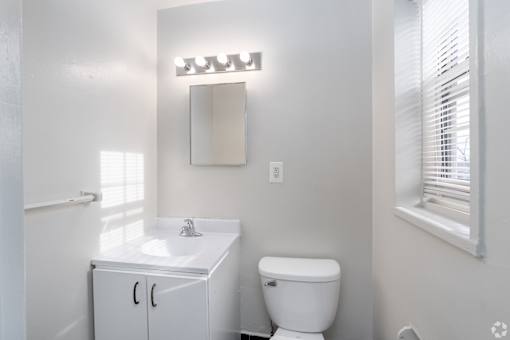 A white bathroom with a toilet, sink, and mirror.