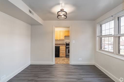 A spacious, empty room with a kitchen in the background.