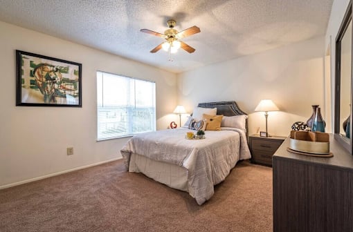 A bedroom with a bed, nightstand, and a ceiling fan.