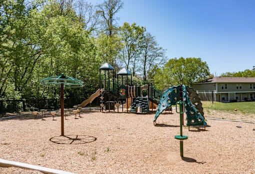 A playground with a green slide, a swing set, and a sandbox.