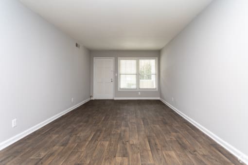 an empty living room with wood flooring and white walls