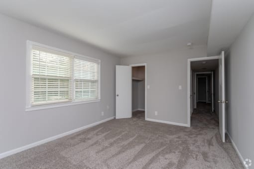 an empty living room with a large window and carpet
