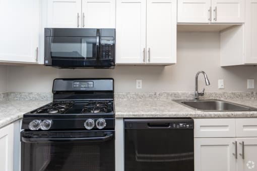 a kitchen with white cabinets and black appliances and a sink