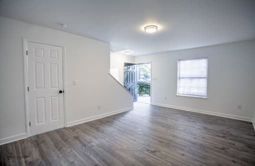 the living room of an empty house with a white wall and wooden floors