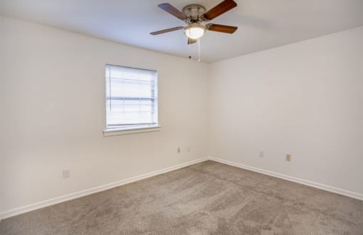 an empty room with a ceiling fan and a window