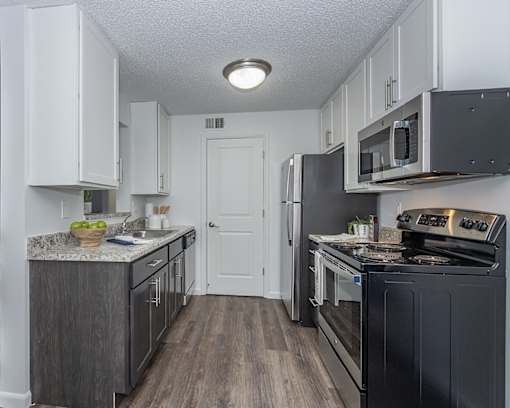 A kitchen with black appliances and white cabinets.