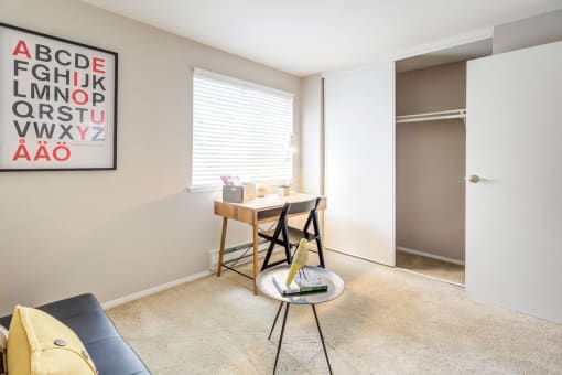 a living room with a desk and chair and a door to a closet