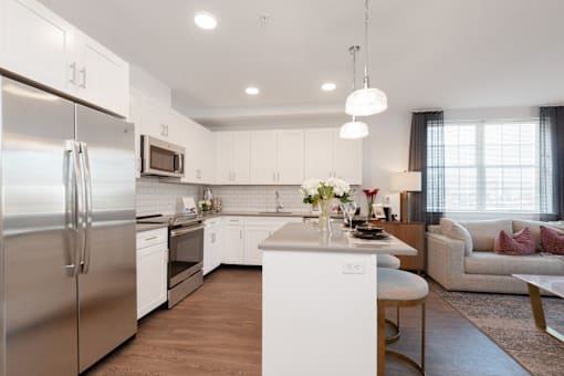 a kitchen and living room with stainless steel appliances and white cabinets