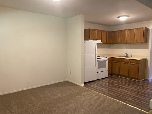 an empty kitchen with white appliances and wooden cabinets