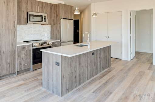 A kitchen with a white countertop and wooden cabinets.