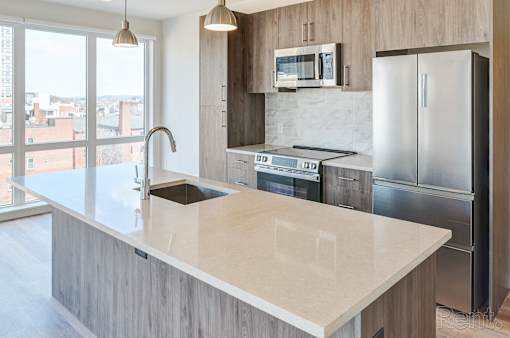 A modern kitchen with a marble countertop and stainless steel appliances.
