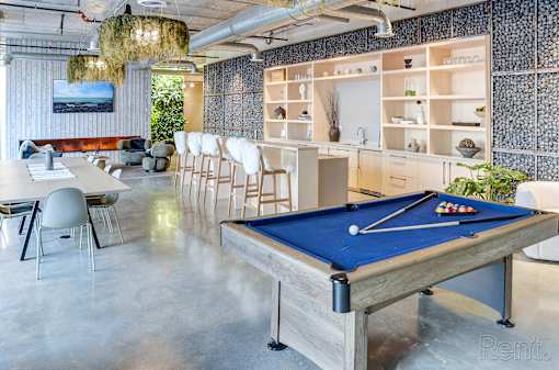 A pool table in a room with a blue cloth and white cues.