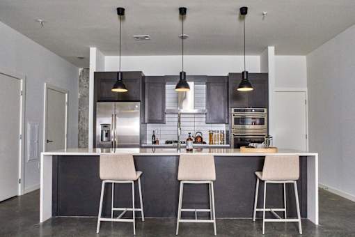 a kitchen with an island with three bar stools at The Audubon New Haven, Connecticut
