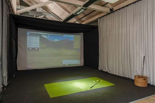 a golf simulator in a room with a screen and a golf ball at The Audubon New Haven, New Haven, 06511