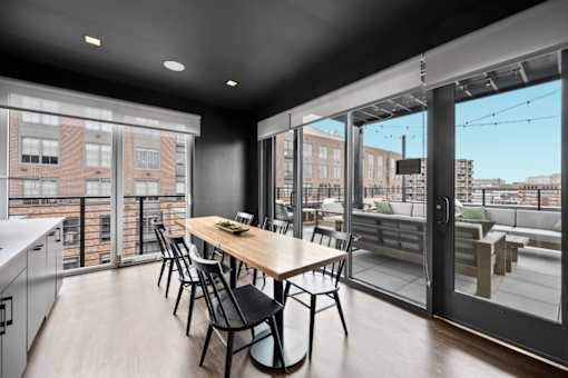 a dining area with a wooden table and chairs and a large window with a balcony at The Audubon New Haven, New Haven, Connecticut