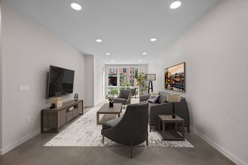 a living room with a gray couch and a tv at The Audubon New Haven, New Haven, 06511