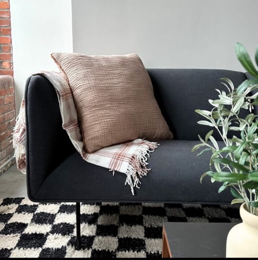 a black couch with a pillow and a blanket on it