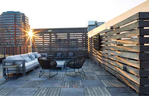 a roof deck with furniture and a building in the background at The Audubon New Haven, Connecticut, 06511