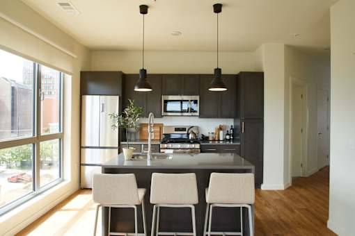 a large kitchen with black cabinets and a counter with four chairs at The Audubon New Haven, New Haven, CT, 06511