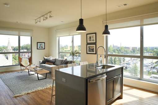 the living room and kitchen of an apartment with a view of the city at The Audubon New Haven, New Haven, CT