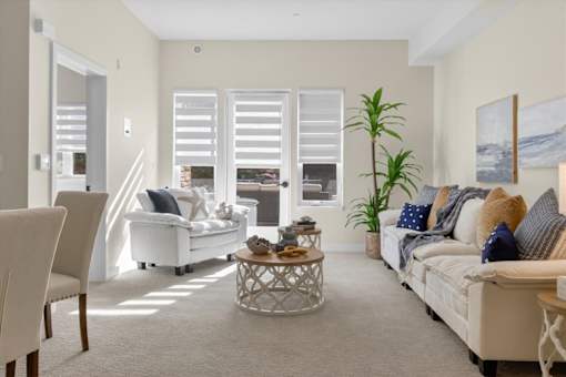 A living room with a white sofa, a wooden chair, and a coffee table.