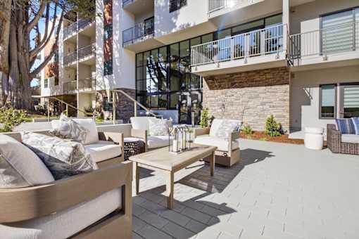 A patio with a couch, table, and chairs in front of a building.