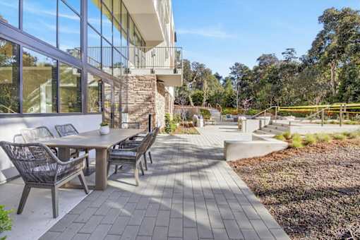 A patio with a table and chairs is surrounded by a garden.