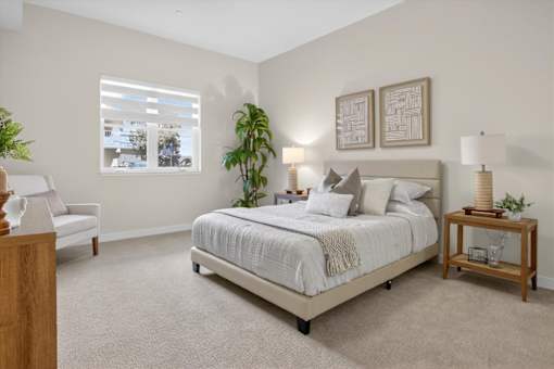 A bedroom with a bed, nightstand, and a chair.