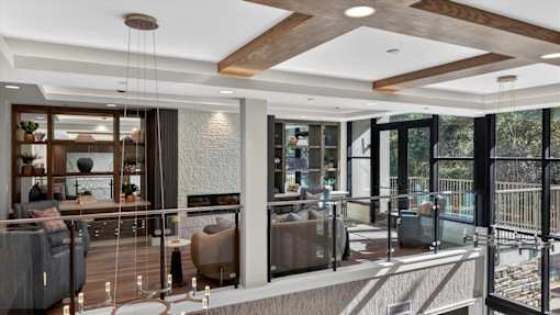 A modern living room with a glass railing balcony.
