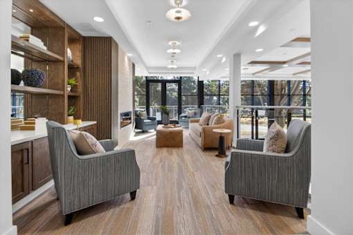 A modern living room with grey couches and wooden floors.